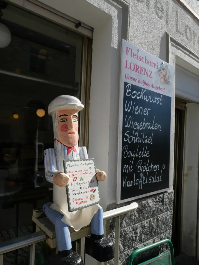 Holzfigur eines Fleischers mit Tafel vor dem Eingang der Fleischerei Lorenz