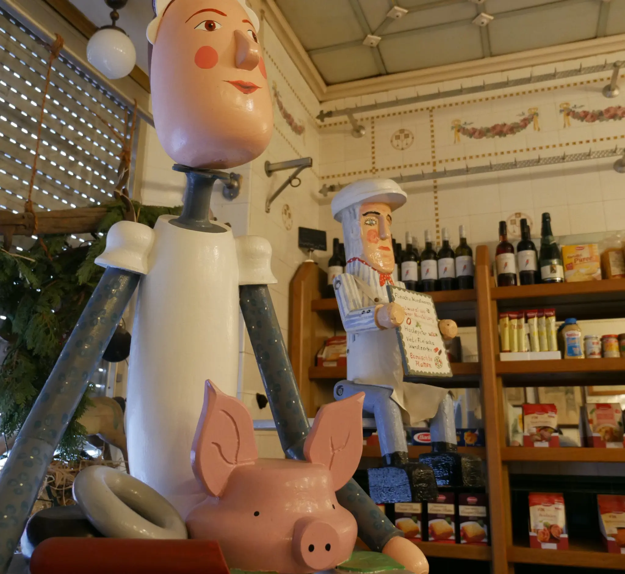 Geschnitzte Fleischerfigur zwischen Regalen im historischen Laden